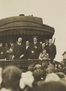 Theodore Roosevelt, with others, standing on back of Railroad car, speaking to crowd, Eugene, Oregon, USA, April 5, 1911