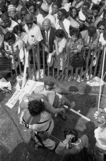 Crowd of African Americans behind a storm fence with police carrying a woman on the other side during March on Washington for Jobs and Freedom, Washington, D.C. USA, photograph by Marion S. Trikosko, ...