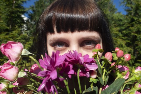 Portrait of Young Adult Woman Peering over Bouquet of Flowers