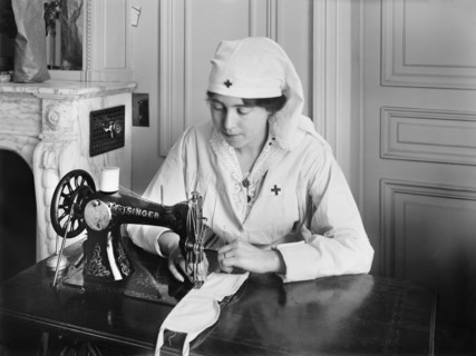 Female American Red Cross Worker stitching eye bandages on Sewing Machine in the American Red Cross Workrooms for Surgical Dressings