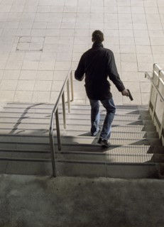 Rear View of Man with Gun walking down Steps