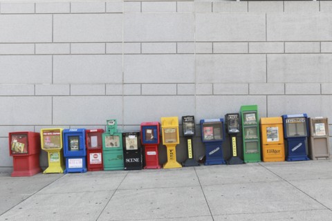 Row of Colorful Newspaper Boxes on Sloping Sidewalk