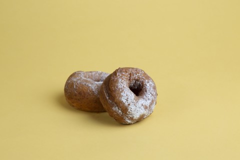 Two Doughnuts with Powdered Sugar on Yellow Background