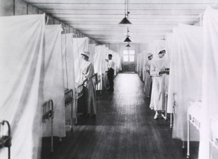 Nurses and Orderlies standing at foot of Beds separated by Sheets, Influenza Ward, 1918