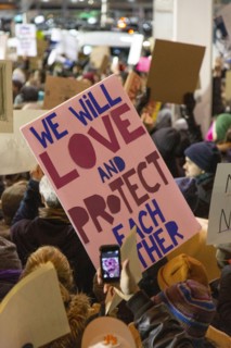 Protester holding Sign "We Will Love and Protect Each Other", Protest against Muslim Travel Ban,