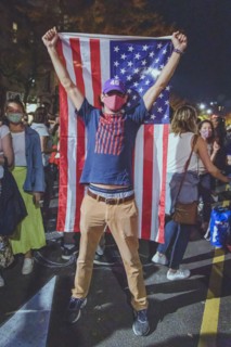 Man holding up American Flag during Celebration of President-Elect Joe Biden at Night, Brooklyn