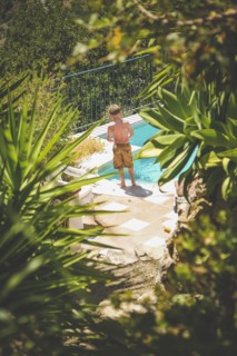 Rear View of Young Shirtless Boy standing near Swimming Pool,