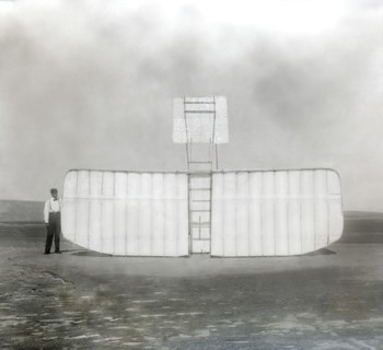 Orville Wright at left wing end of upended glider