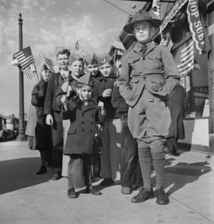 Boy Scout leading group of Young boys wearing garrison caps and holding American Flags at start of Parade and Flag Dedication Ceremony at Office of Civil Defense Headquarters