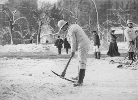Man clearing street with pickaxe after snow storm