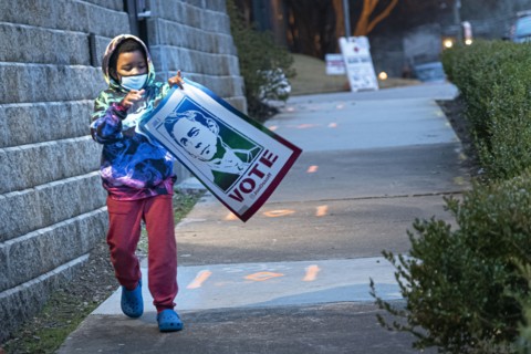 Young Boy carrying Congressman John Ossoff Banner after Campaign Rally
