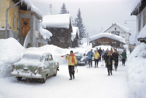 Group of Skiers walking through Village on Snowy Day