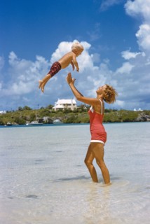 Woman playfully tossing Young Boy in Air at Beach