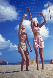 Young Adult Man and Young Adult Woman playing Volleyball on Beach