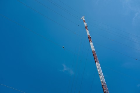 Low Angle View of Communications Tower with Guide Wires against Blue Sky