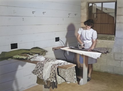 Young Adult Woman ironing Clothes at Laundry Facilities in Utility Building
