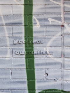 Protect Journalists quote on brick wall covered in paint and graffiti
