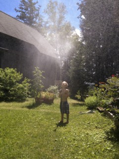 Young boy playing with sprinkler hose in yard