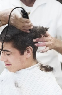 Young U.S. soldier who had just been drafted into U.S. Army getting head shaved by barber