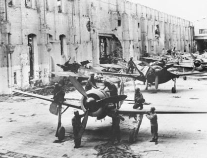 U.S. Army Quartermaster troops inspecting found Focke-Wulf fighter planes grounded either by rubble or lack of gasoline
