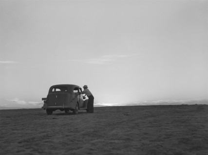 Man standing at car window talking to driver on the plain at sunset