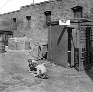Two children playing marbles outside public toilet