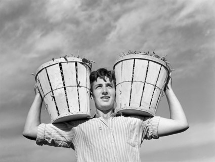 Field worker with two baskets of string beans
