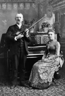 Portrait of Man holding Violin and Woman seated at Piano