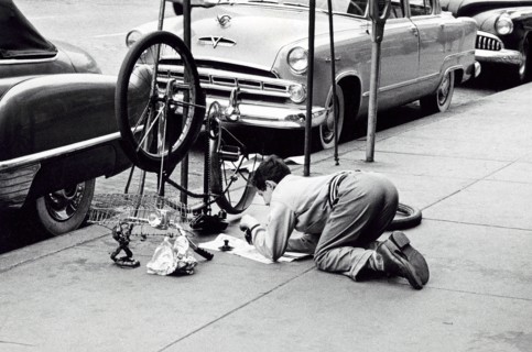Man fixing bicycle on sidewalk