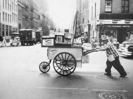 Man pushing hot dog cart across street