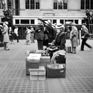 Woman sitting on luggage while waiting for train, Pennsylvania Station, New York City, New York,