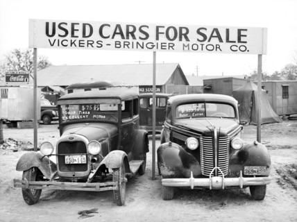Used cars for sale with signs and prices at service station on main highway near Alexandria,