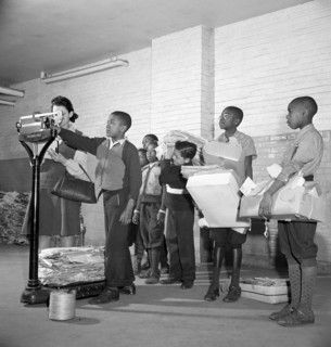 Students lined up to weigh collected scrap paper at school during Scrap Salvage Campaign, Victory