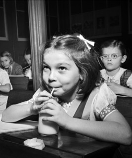 Young girl drinking glass of milk in classroom, New York City, New York, USA, Marjory Collins, U.S.
