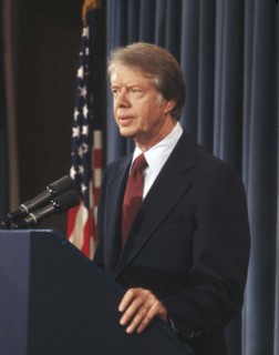 U.S. President Jimmy Carter at podium during news conference, half-length profile portrait,