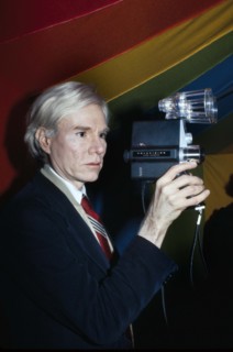 American pop artist Andy Warhol, half-length portrait holding Polaroid Polavision camera, Bernard