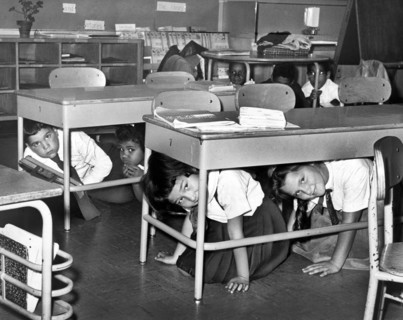 Young schoolchildren crawl under desks during air raid drill, P.S. 58, Carroll & Smith Streets,
