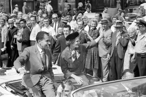 U.S. Vice President Richard Nixon with his wife Pat Nixon wave to crowds while riding in open car