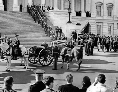 Flag-draped casket of late U.S. President John Kennedy carried by horse-drawn caisson, arriving at