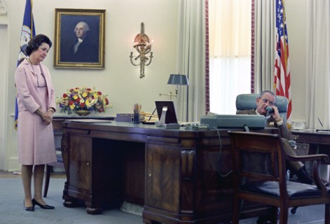 U.S. First Lady Claudia "Lady Bird" Johnson looking on as U.S. President Lyndon Johnson telephones