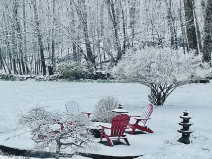 Snowy patio and landscape with red Adirondack chairs