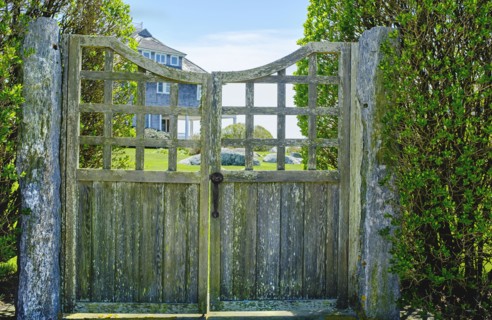 Weathered wood gate with large home in background
