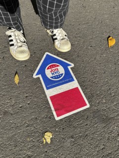 High angle view of person standing near NYC board of elections early voting arrow sign adhered to