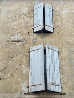 Blue weathered wood shutters on cracking building façade, Dordogne, France