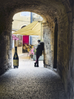 Rear view of a man standing at the end of an alley near an outdoor café, Sarlat-la-Canéda,