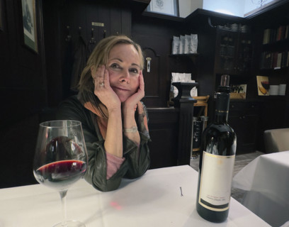 Mid-adult woman sitting at table having a glass of wine