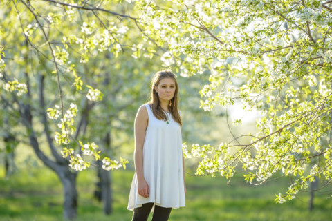 Portrait of Young adult woman in blossoming cherry orchard