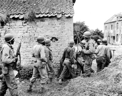 Platoon of black American troops surrounding French farm house as they prepare to eliminate German