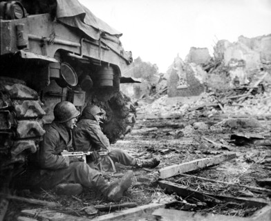 American Infantrymen seek shelter behind tank during enemy fire, Geich, Germany, U.S. Army Signal