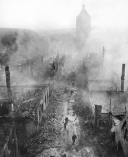 U.S. infantrymen of the 255th Infantry Regiment moving down street to hunt out Hun after recent